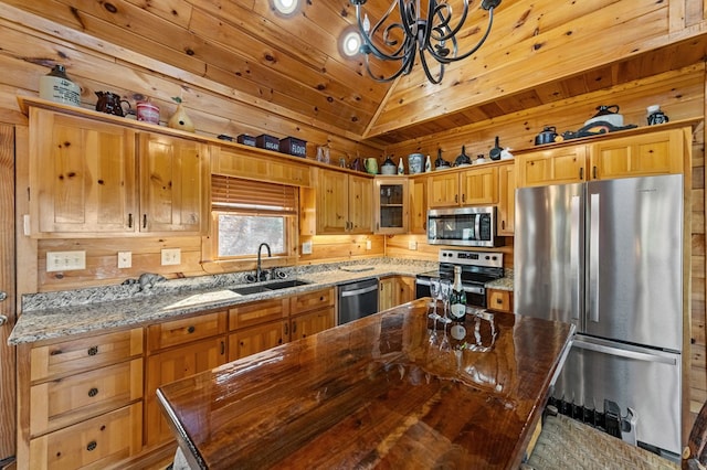 kitchen featuring sink, appliances with stainless steel finishes, hanging light fixtures, a kitchen island, and dark stone counters