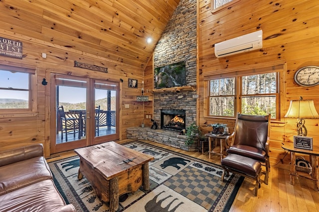 living room featuring wood ceiling, a wall unit AC, wood walls, a fireplace, and light wood-type flooring