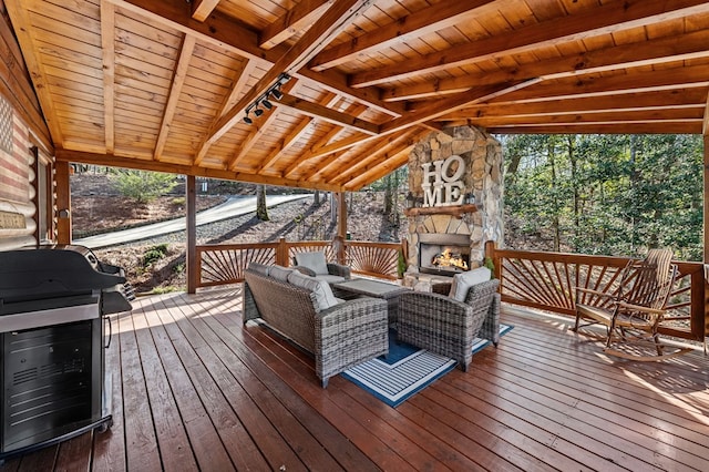 sunroom / solarium with a healthy amount of sunlight, an outdoor stone fireplace, wooden ceiling, and vaulted ceiling with beams