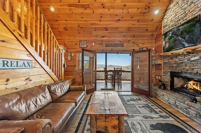 living room with hardwood / wood-style floors, wooden walls, high vaulted ceiling, a fireplace, and wooden ceiling