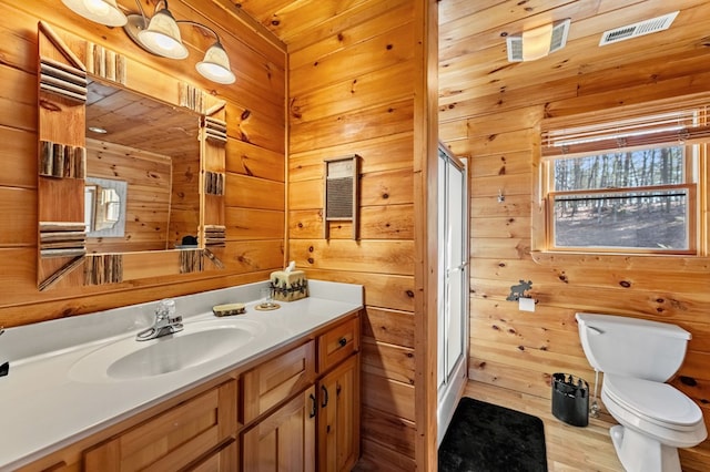 bathroom featuring vanity, toilet, an enclosed shower, and wood walls