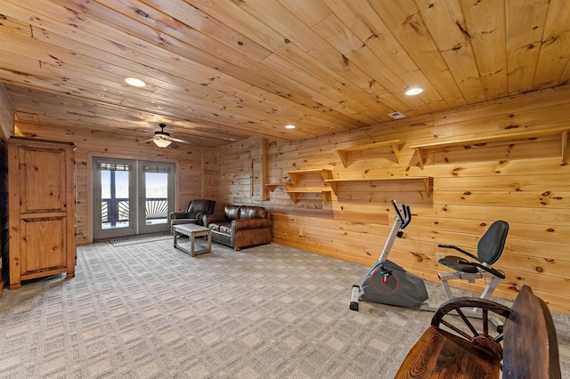 exercise room featuring ceiling fan, light colored carpet, wood ceiling, and wood walls