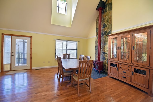 dining room with hardwood / wood-style floors, ornamental molding, and high vaulted ceiling