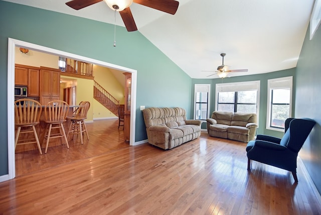 living room featuring ceiling fan, lofted ceiling, and light hardwood / wood-style floors