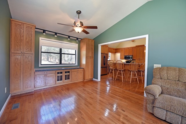 unfurnished living room featuring ceiling fan, lofted ceiling, track lighting, and light wood-type flooring