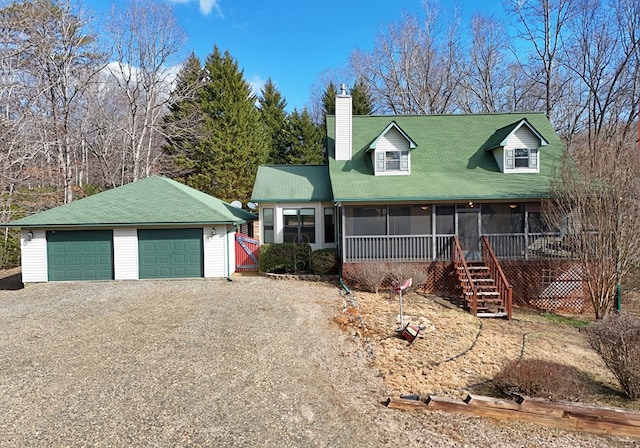 view of front of home with a garage, a sunroom, and an outdoor structure