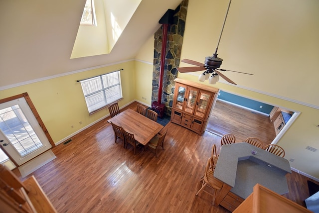 dining room with ceiling fan, hardwood / wood-style floors, and high vaulted ceiling