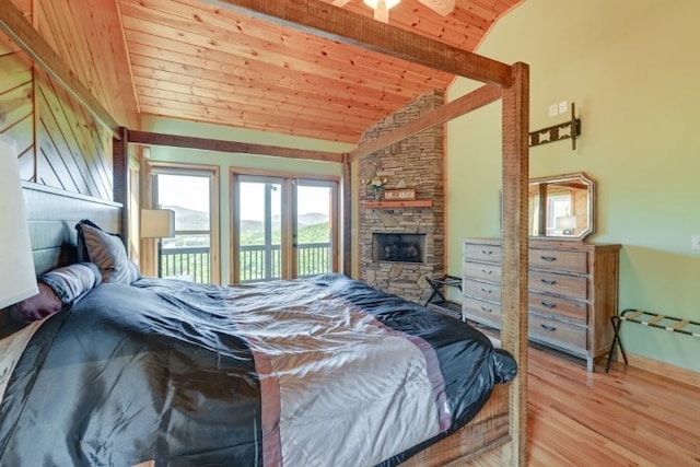 bedroom featuring access to outside, wood-type flooring, vaulted ceiling with beams, a stone fireplace, and wooden ceiling