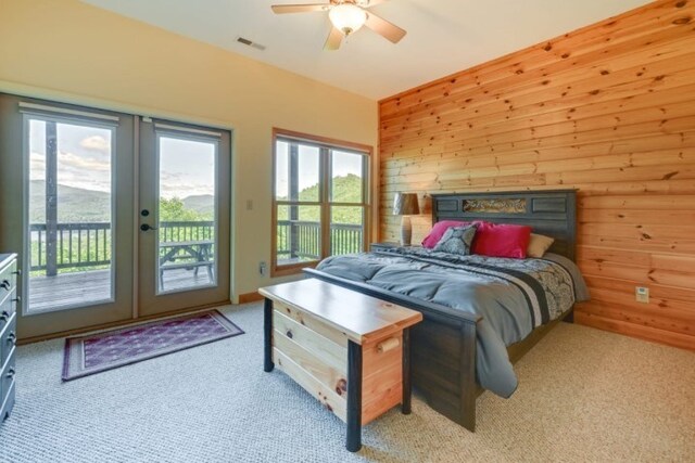 bedroom featuring french doors, multiple windows, access to outside, and wood walls