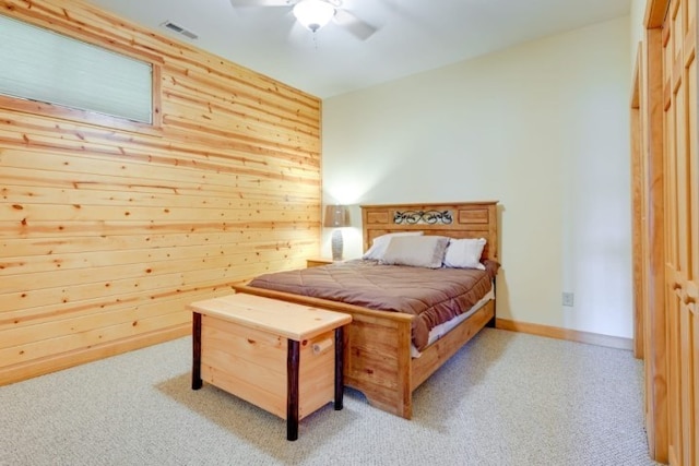 bedroom featuring a closet, ceiling fan, wood walls, and light colored carpet