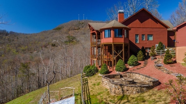 rear view of house with a mountain view and an outdoor fire pit