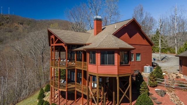 rear view of property featuring a wooden deck, a sunroom, and central AC