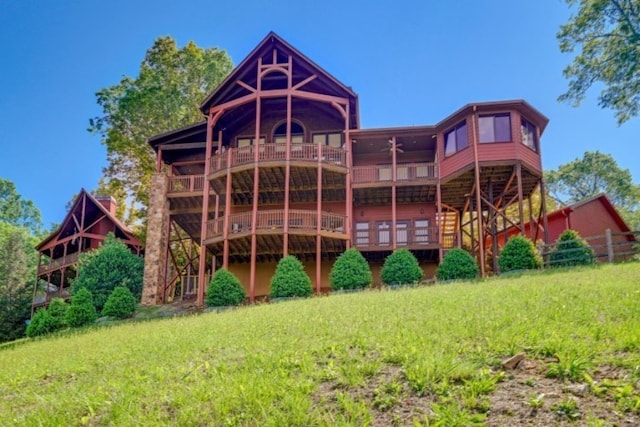 rear view of property featuring a wooden deck and a lawn