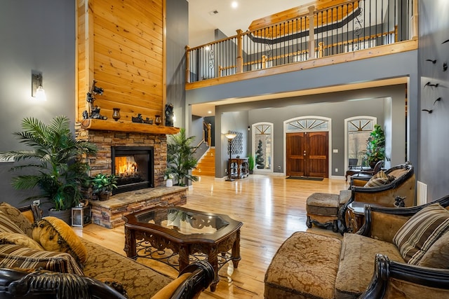 living room with a towering ceiling, a fireplace, and light hardwood / wood-style floors