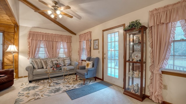 living area with vaulted ceiling, ceiling fan, a healthy amount of sunlight, and light colored carpet