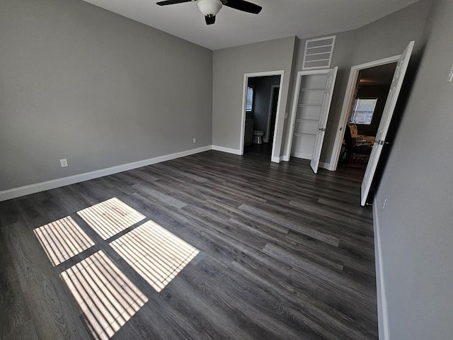 unfurnished bedroom featuring ceiling fan, dark wood-type flooring, and connected bathroom