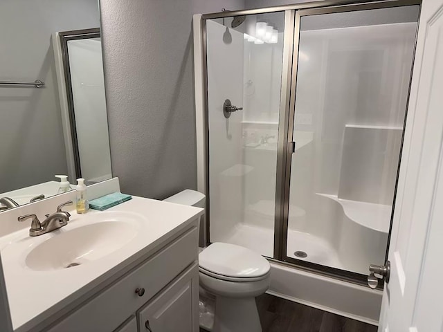 bathroom featuring hardwood / wood-style floors, vanity, toilet, and walk in shower