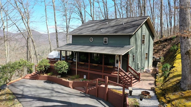 view of front of property with a mountain view, a porch, and roof with shingles
