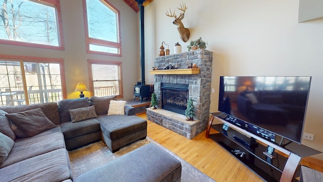 living area with a wood stove, a towering ceiling, and wood finished floors