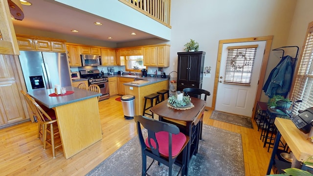 kitchen featuring a breakfast bar area, recessed lighting, stainless steel appliances, and light wood finished floors