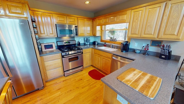 kitchen with recessed lighting, light brown cabinetry, appliances with stainless steel finishes, a sink, and light wood-type flooring