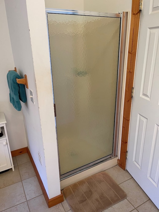 full bathroom with a stall shower, tile patterned flooring, and baseboards