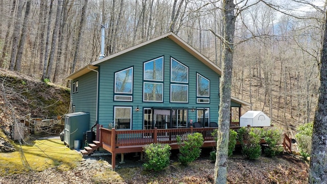 back of house featuring a forest view and a wooden deck