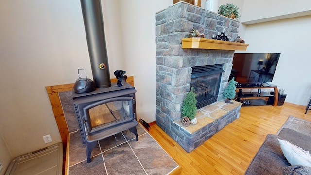 living room with a wood stove, wood finished floors, and a fireplace