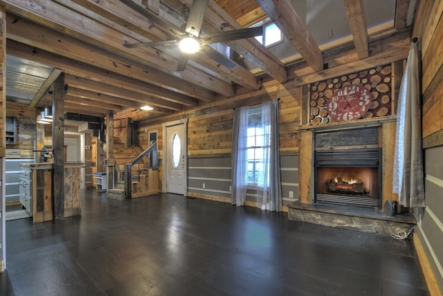 interior space with wood walls, ceiling fan, beamed ceiling, and dark hardwood / wood-style flooring