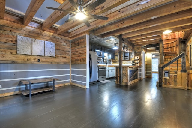 interior space with wood walls, ceiling fan, and stainless steel refrigerator