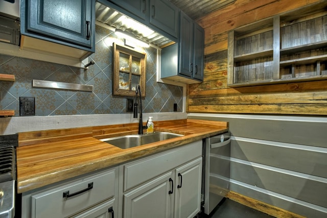 kitchen featuring butcher block counters, backsplash, wooden walls, sink, and stainless steel dishwasher