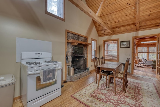 kitchen with white range with gas cooktop, a fireplace, light hardwood / wood-style flooring, and high vaulted ceiling