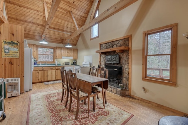 dining room with heating unit, beam ceiling, high vaulted ceiling, sink, and light hardwood / wood-style floors