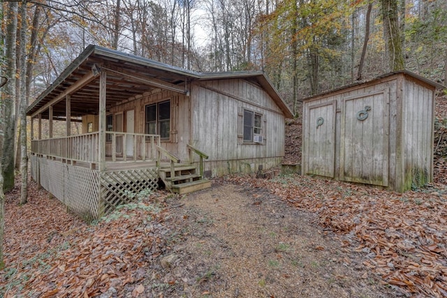 view of front of property featuring a deck and a storage shed