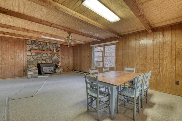 dining room featuring wooden walls, a wood stove, and carpet