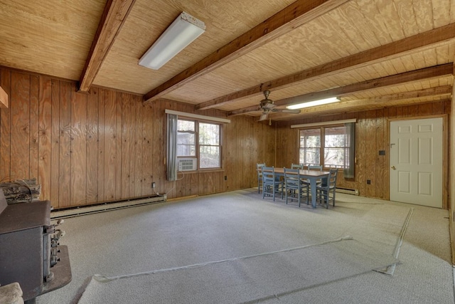 unfurnished dining area featuring wood walls, wooden ceiling, beam ceiling, a wood stove, and a baseboard heating unit