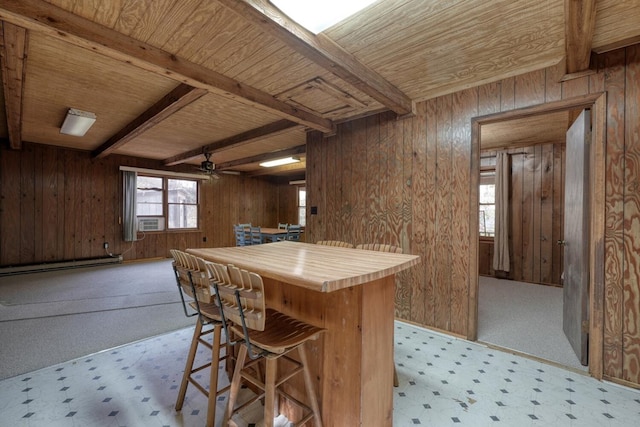 kitchen featuring beamed ceiling, wood walls, and a breakfast bar area