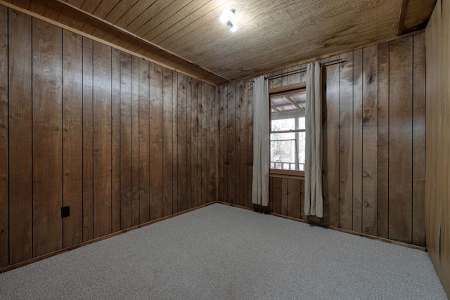 carpeted spare room with wooden walls and wood ceiling