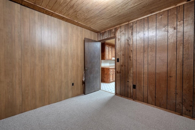 unfurnished room featuring wood walls, light carpet, and wood ceiling