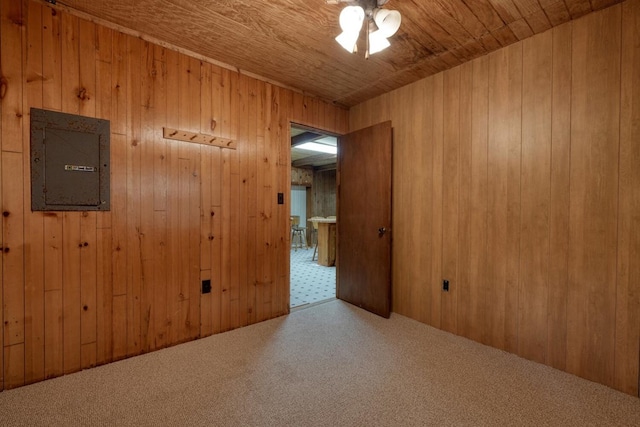 carpeted empty room with electric panel, wooden walls, and wooden ceiling