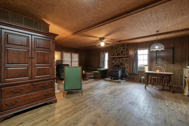 interior space with a wood stove, hardwood / wood-style flooring, and wooden walls