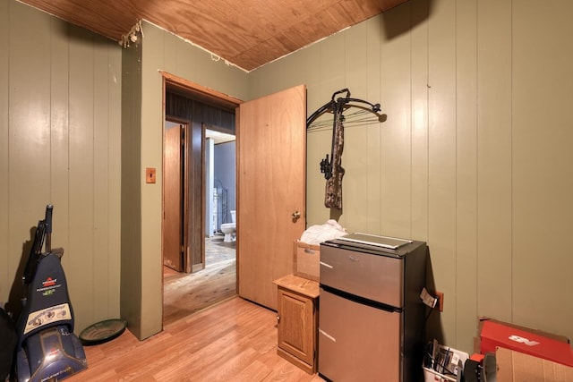 corridor with light hardwood / wood-style floors, wooden walls, and wooden ceiling