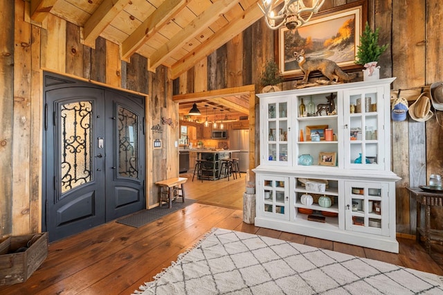 entrance foyer with hardwood / wood-style flooring, beam ceiling, wooden ceiling, french doors, and wood walls