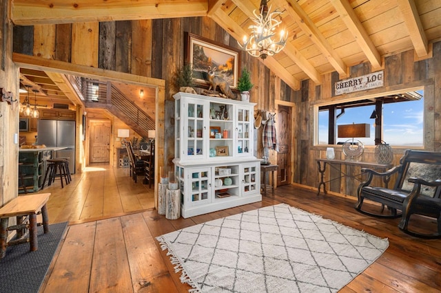 living area featuring a notable chandelier, wood-type flooring, and wood walls