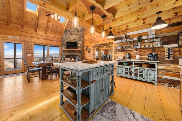 kitchen featuring hanging light fixtures, a skylight, wooden walls, a center island, and light hardwood / wood-style floors