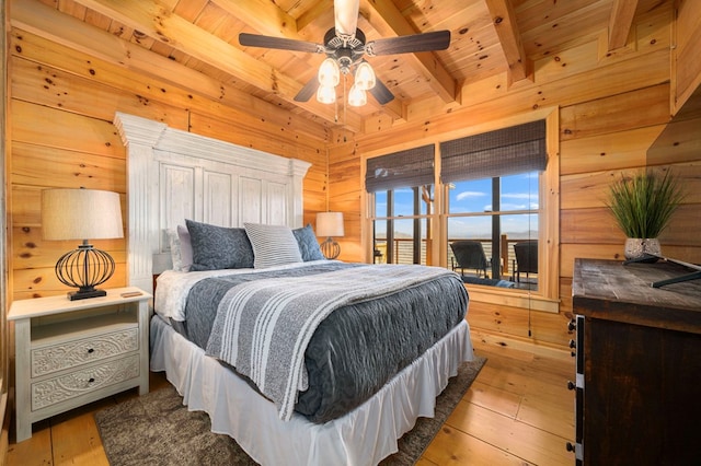 bedroom featuring light hardwood / wood-style flooring, beam ceiling, wooden walls, and wooden ceiling