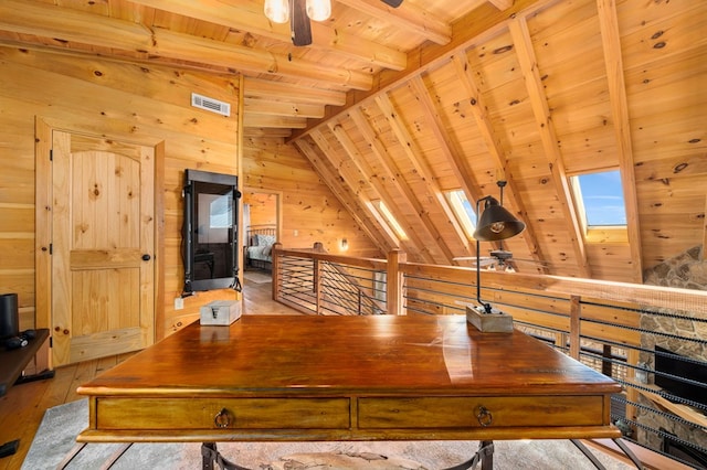 office space featuring wood ceiling, ceiling fan, wooden walls, vaulted ceiling with skylight, and light hardwood / wood-style floors