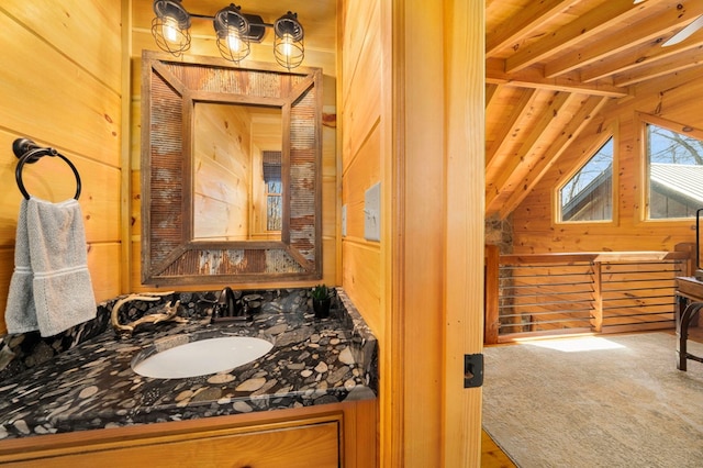 bathroom with vanity, vaulted ceiling with beams, and wooden walls