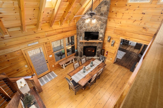 living room with beamed ceiling, a stone fireplace, hardwood / wood-style floors, and wood walls