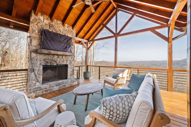 interior space featuring ceiling fan, vaulted ceiling with beams, wooden ceiling, and an outdoor stone fireplace